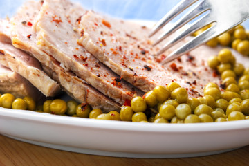 Oven roasted ham with peas on dish with fork
