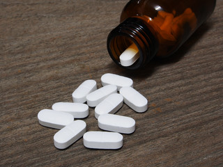 Pills spilling out of a pill bottle on wooden table