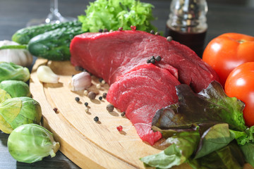 Raw beef meat with vegetables on wooden table
