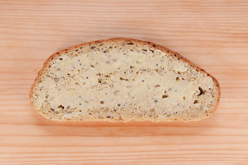 Slice of buttered bread on a wooden table