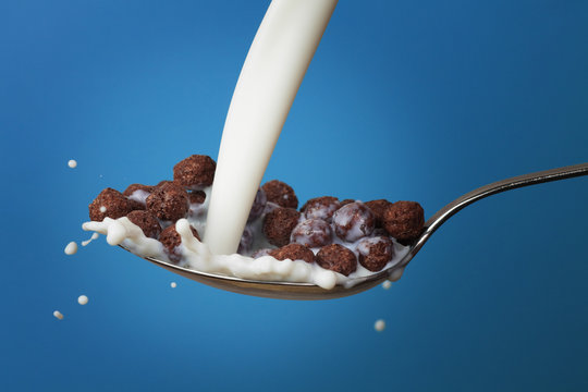 milk splashing into spoon full of chocolate cornballs