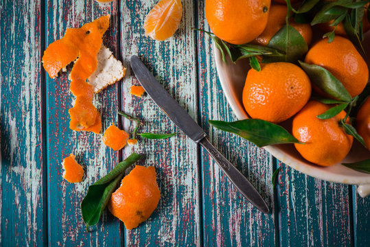 peeling mandarines with knife from above on table