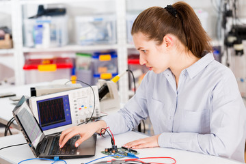 Woman  with a tester and a printed circuit board