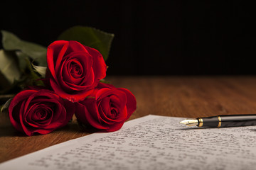 still life of a fountain pen, paper and flowers roses