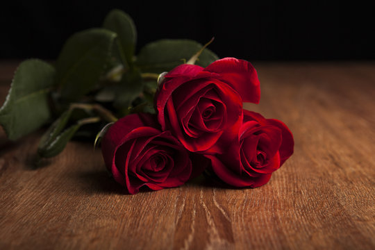 bouquet of roses lying on a wooden table on a black background