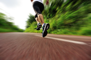 Obraz premium young fitness woman legs running at forest trail 