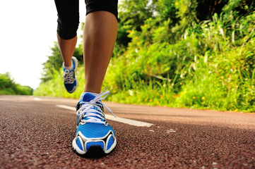 	young fitness woman legs running at forest trail 