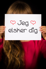 Child holding sign with Danish words Jeg Elsker Dig - I Love You