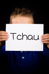 Child holding sign with Portuguese word Tchau - See You Later