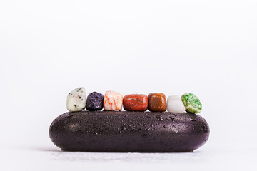Row Of Chakra Crystals on hot massage black stones - 75558348