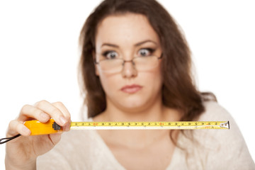 young woman is stunned by the size shown on the measuring tape