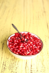 Juicy pomegranate seeds, on yellow wooden table