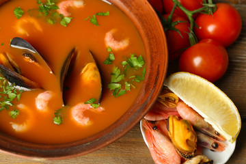 Tasty soup with shrimps, mussels, tomatoes and black olives in