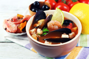 Tasty soup with shrimps, mussels, tomatoes and black olives in
