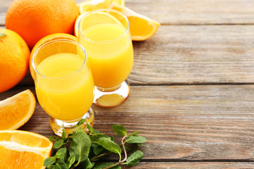 Glass of orange juice and slices on wooden table background