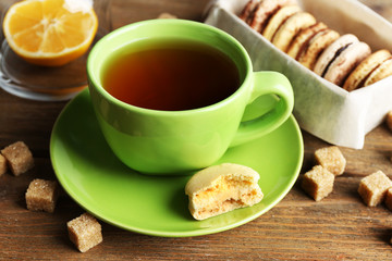 Colorful macaroons with cup of tea on wooden background
