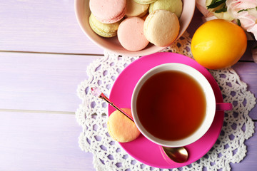 Colorful macaroons with cup of tea on wooden background