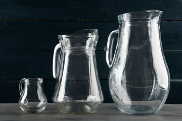 Glass jugs on dark color wooden background