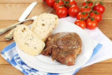 Roasted meat and vegetables on plate, on wooden table