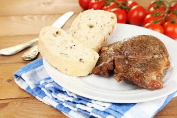 Roasted meat and vegetables on plate, on wooden table