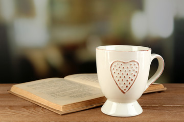 Cup of tea and book on table, on dark background