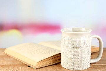 Cup of tea and book on table, on bright background