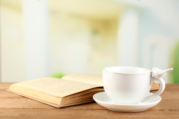 Cup and book on table, on bright background