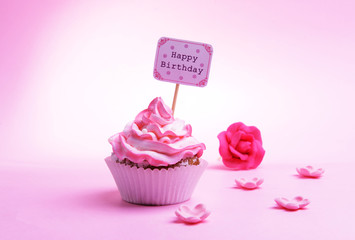 Delicious cupcake with inscription on table on pink background