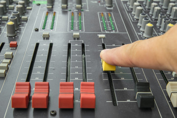 Finger pushing a mixing desk slide. Selective focus