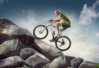 Sport background. Cyclist climbing on a rock.