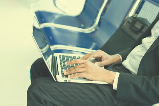 Businessman in airport waiting lounge typing on laptop