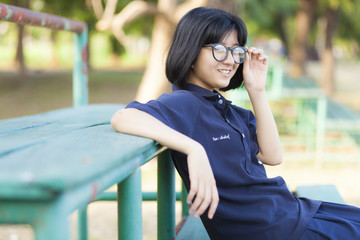Girl wearing glasses sitting on the bench.