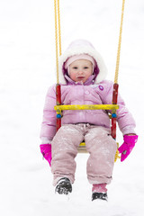 little girl sitting on swing in winter