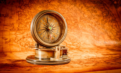 Vintage compass lies on an ancient world map.