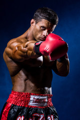 Strong muscular boxer in red boxing gloves. A man in a boxer's s - obrazy, fototapety, plakaty