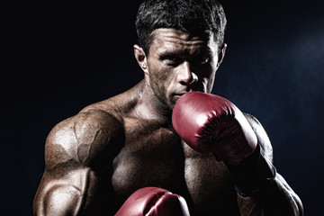 Strong muscular boxer in red boxing gloves. A man in a boxing st
