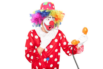 Young surprised clown holding a telephone speaker