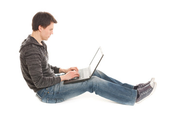 young handsome man works at laptop sitting on the floor