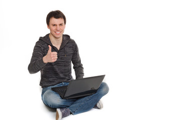 young handsome man works at laptop sitting on the floor