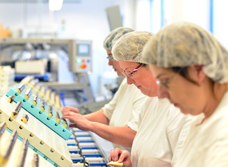 Arbeiterinen verpacken Pralinen in einer Fabrik