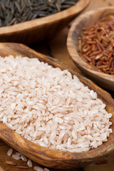 pink unpolished rice in a wooden bowl, top view