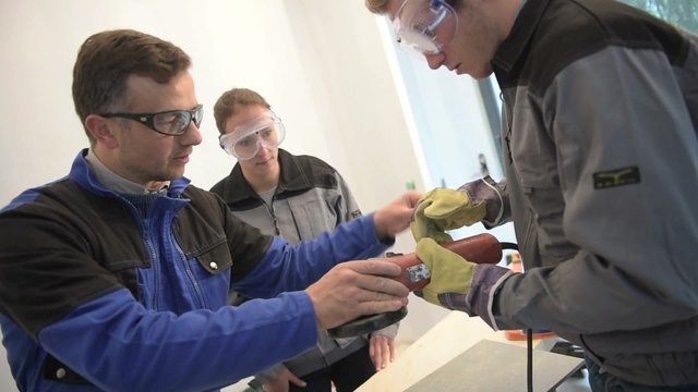 Teacher with students in workshop using electric tile saw