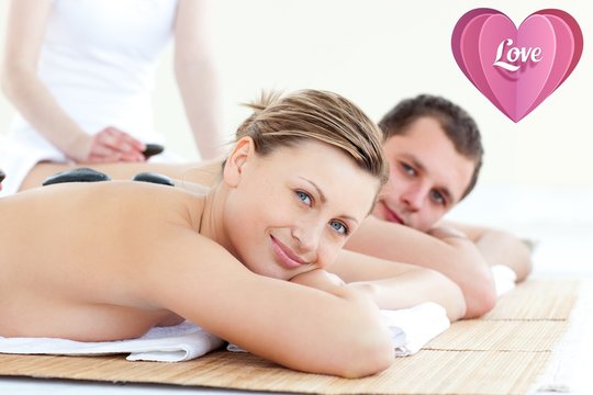 Composite image of smiling young couple having a stone massage