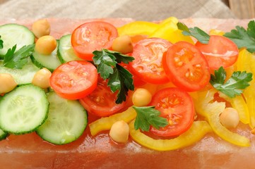 Vegetable salad on pink salt block