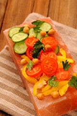 Vegetable salad on pink salt block on stripe napkin