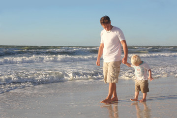 Young Child Holding Father's Hand While Walking in Ocean on Beac