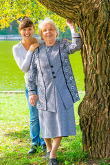 granddaughter and grandmother posing in a park near the tree