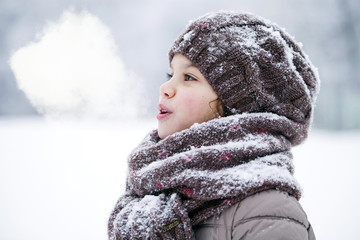 Happy little girl on the background of a winter park