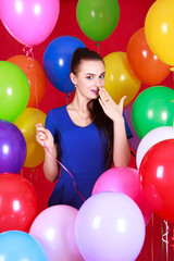 Fototapeta na wymiar Portrait of a young attractive woman among many bright balloons