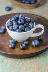 Blueberries in a cup on a wooden table.